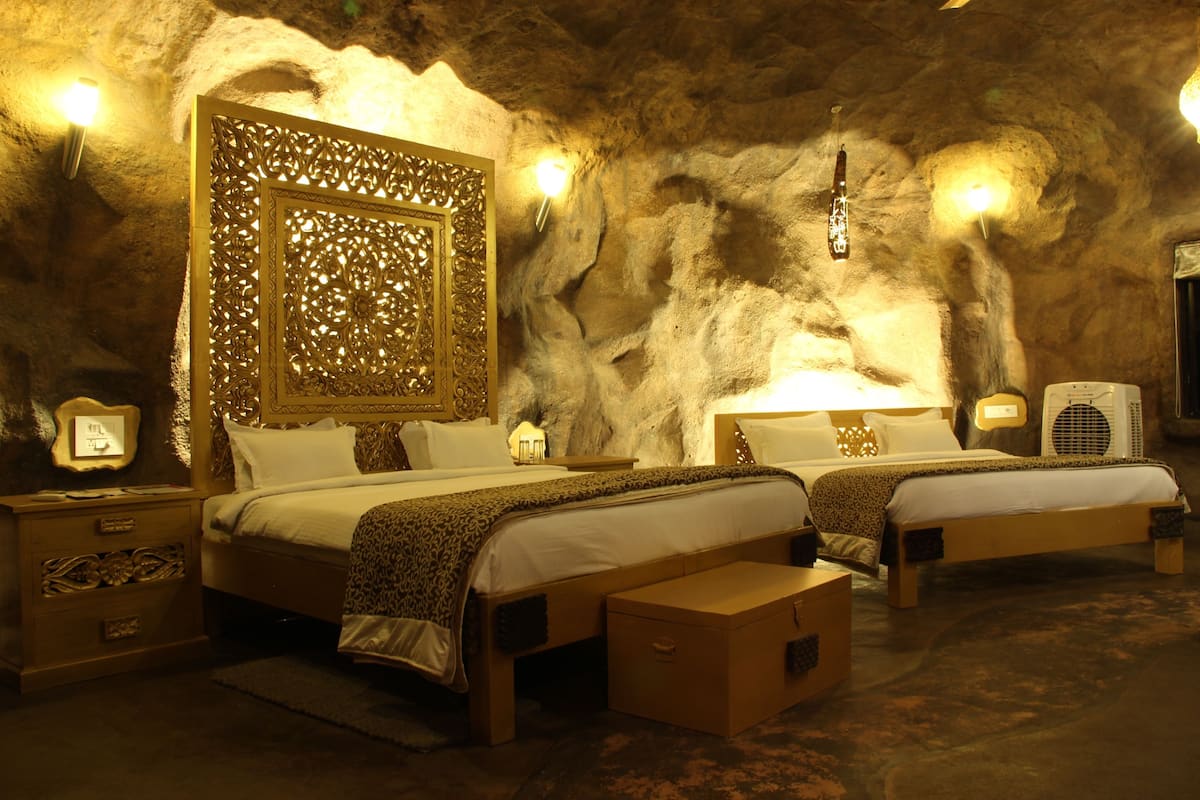A room with two beds, a decorative wall panel, and wall-mounted lights.
