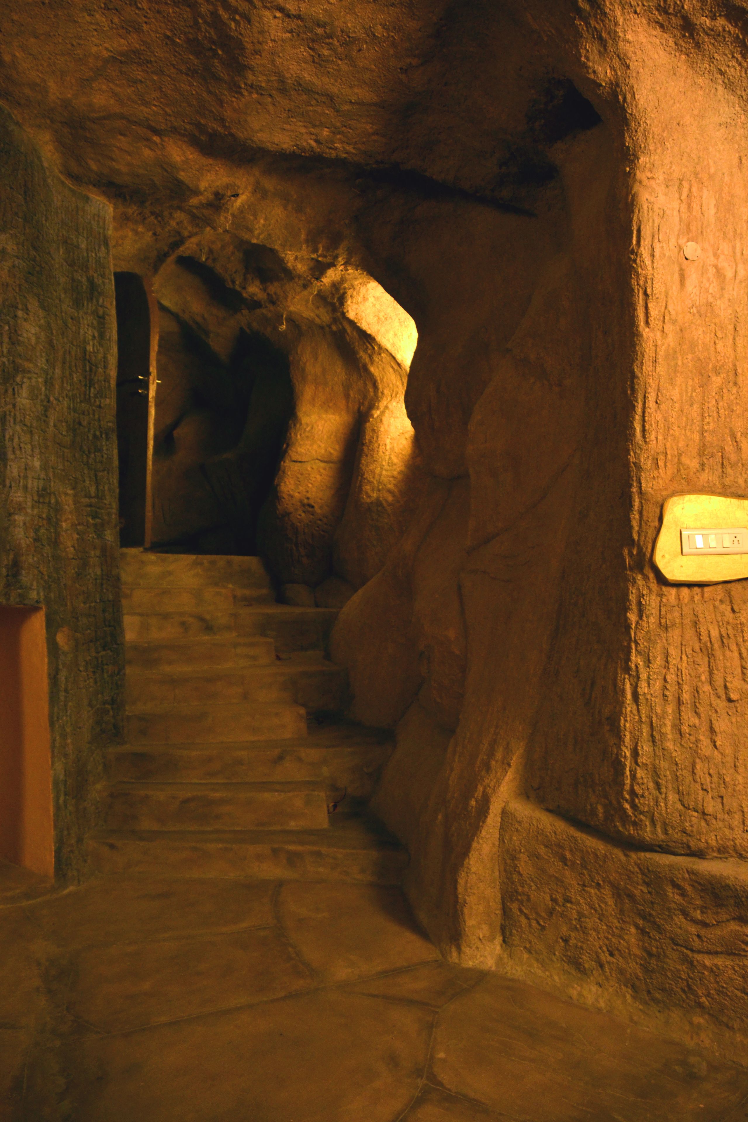 A stone staircase in a cave-like structure with a sign on the wall.