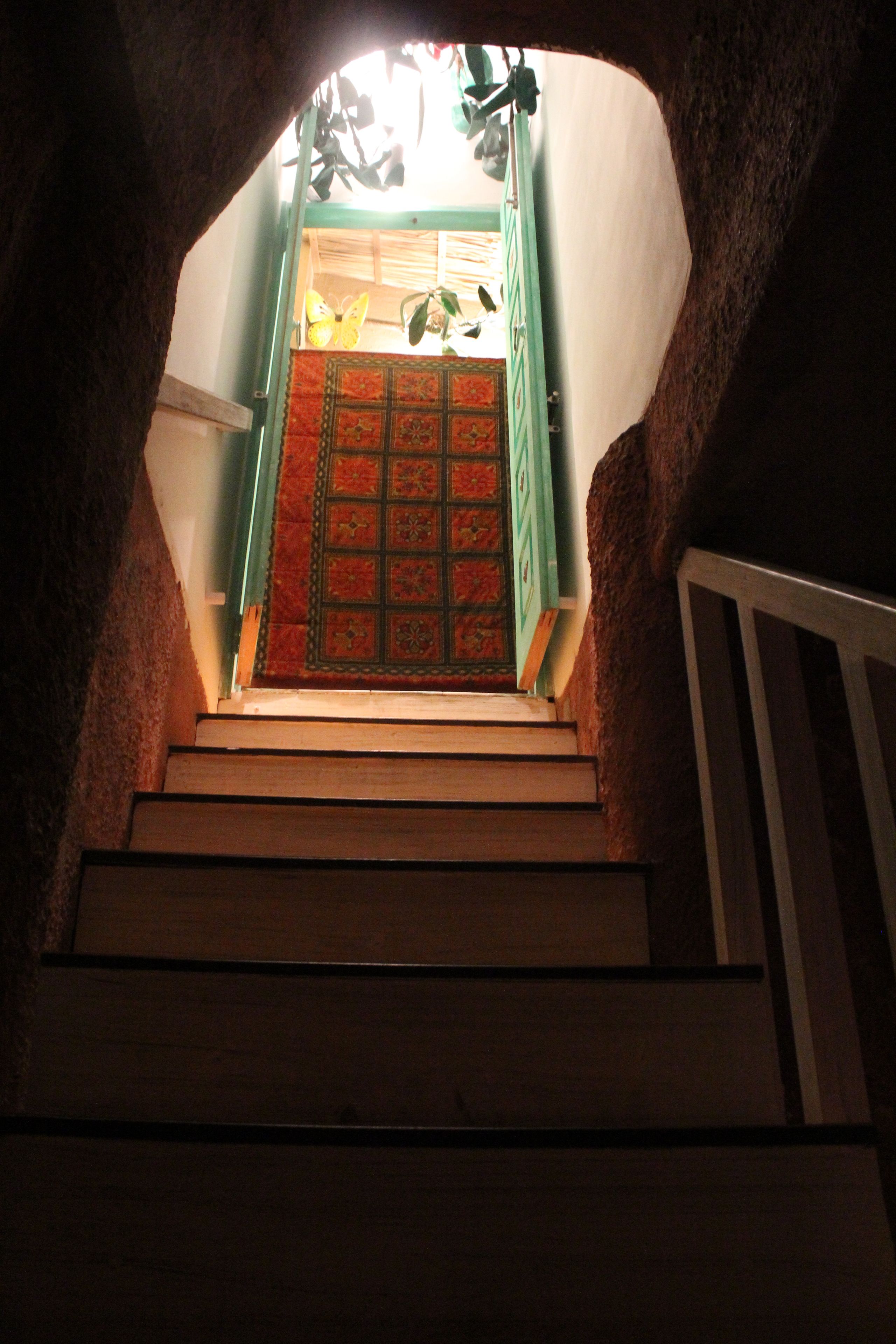 Eine Treppe führt zu einem Raum mit einem gemusterten Teppich und grünen Türen.