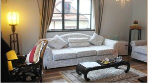 Un salon avec un canapé, une table basse, une lampe et une fenêtre avec des rideaux.