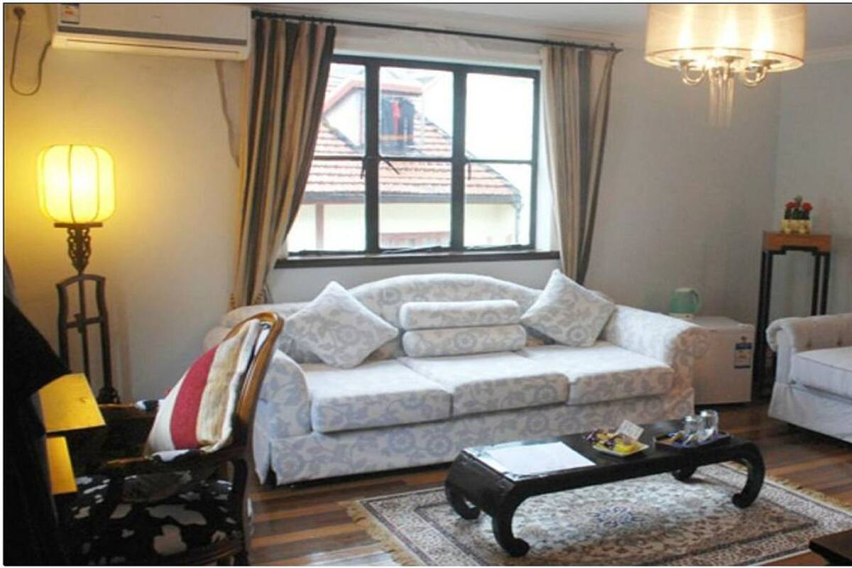 A living room with a sofa, a coffee table, a lamp, and a window with curtains.