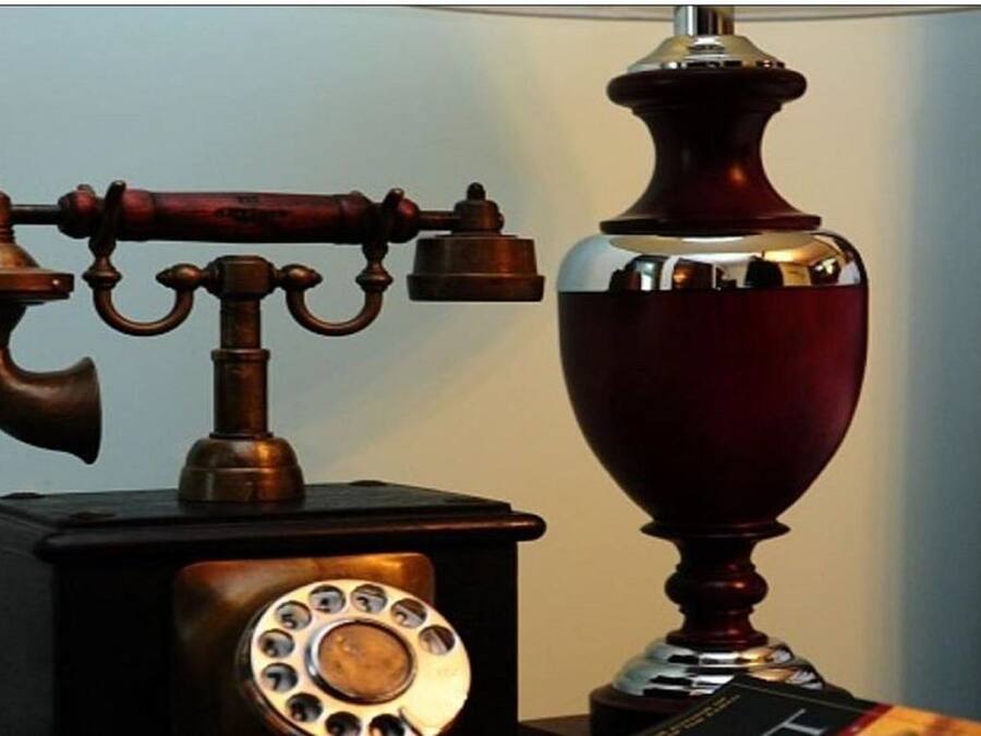 Ein altes Telefon mit Wählscheibe und einer Zierblume.