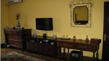 A room with a wooden dresser, a television, a mirror, and a small table with decorative items.