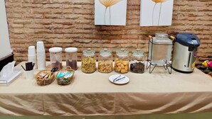 A buffet setup with various food items and drink dispensers on a table against a brick wall. - Sabai Hotel (Nakhon Ratchasima)