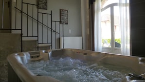 A hot tub with a view of a staircase and a window with curtains. - Gîte du Domaine de La Maison Neuve (Saint-Jean-Saint-Germain)