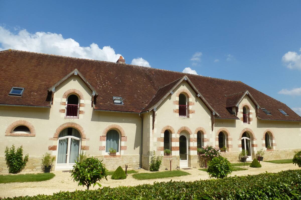 A building with a tiled roof, multiple arched windows, and a well-maintained garden.