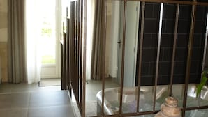 A hotel lobby with a stone wall, a tiled floor, a metal gate, and a large vase. - Gîte du Domaine de La Maison Neuve (Saint-Jean-Saint-Germain)