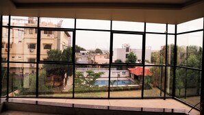 Ein Zimmer mit großen Fenstern und Blick auf ein Wohngebiet, einschließlich eines Schwimmbeckens und Gebäuden.