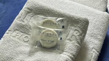Una toalla blanca con una bolsa transparente que dice 'Caicara Hotel' y un jabón.