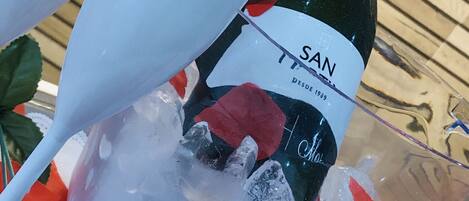 A bottle of San wine in an ice bucket with two Caicara Hotel glasses.
