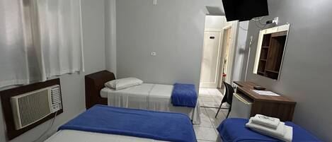 Une chambre d’hôtel avec deux lits, un bureau, un miroir et une télévision.