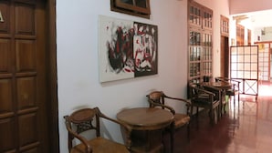 A dining area with wooden furniture and a large abstract painting on the wall. - Sartika Hotel (Yogyakarta)