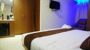 A hotel room with a large bed, a TV mounted on the wall, and a wooden wardrobe. - Haywizz Port Blair - Port Blair (Port Blair)