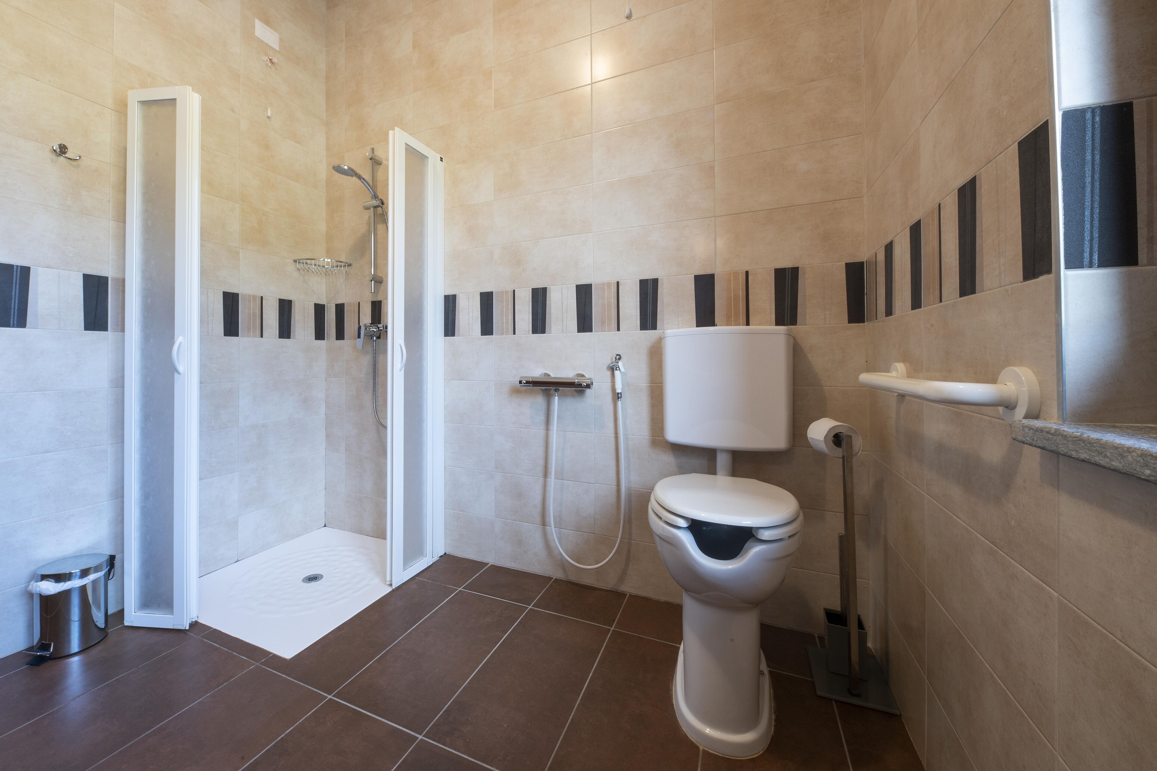 Un baño moderno con ducha, inodoro y secador de manos.