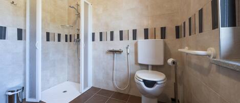 Un baño moderno con ducha, inodoro y secador de manos.