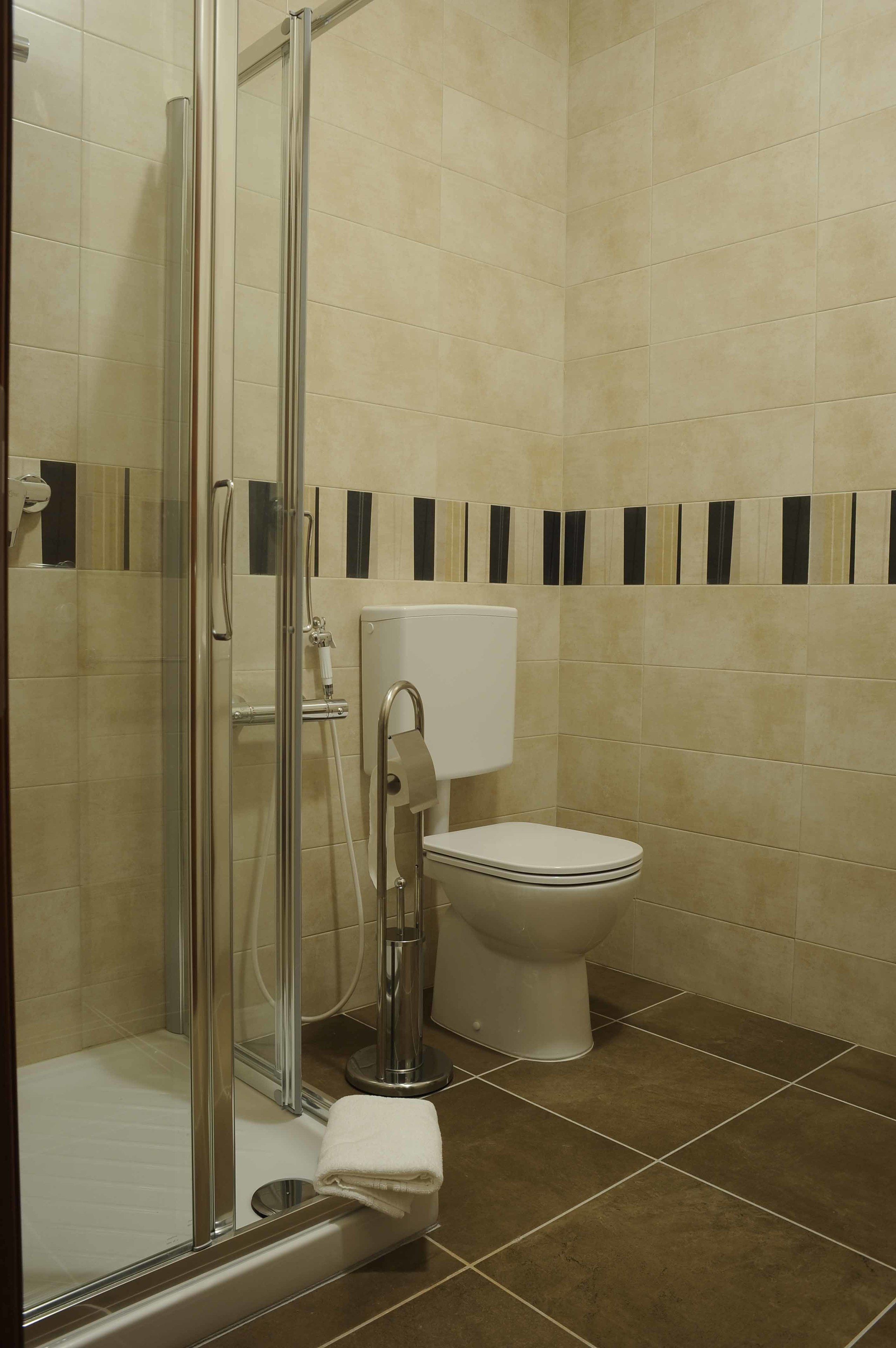 Une salle de bain avec une douche à parois de verre, des toilettes et une serviette sur le sol.