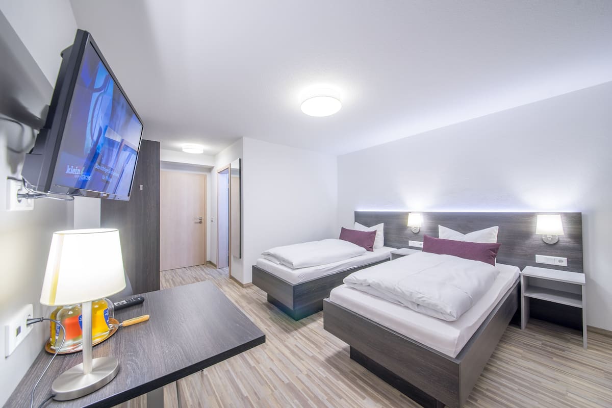 Ein Hotelzimmer mit zwei Betten, einem Fernseher, einer Lampe und einem Nachttisch.