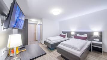 A hotel room with two beds, a TV, a lamp, and a bedside table.