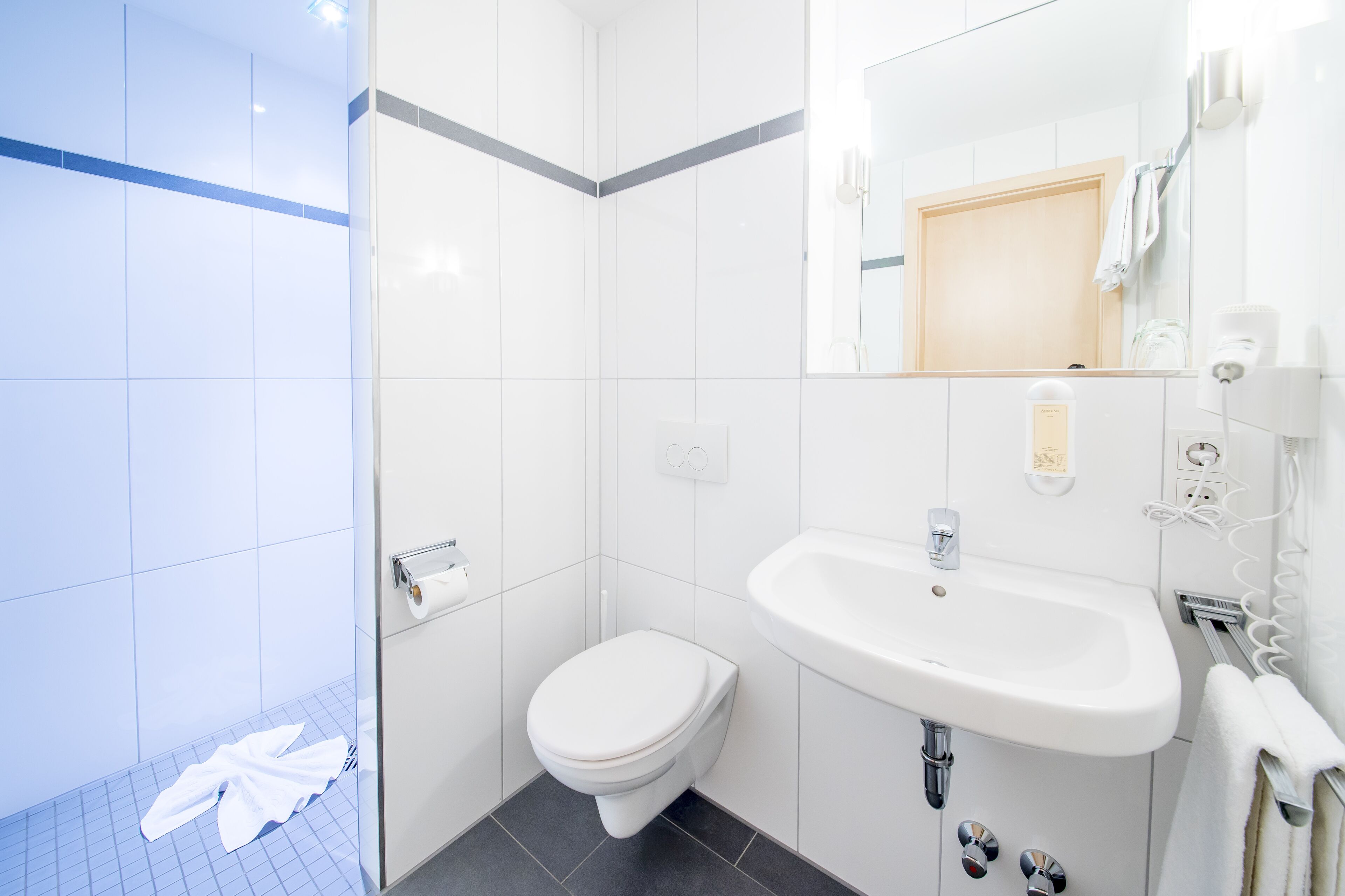 Un baño moderno con lavabo, inodoro y ducha blancos.
