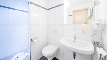 Un baño moderno con lavabo, inodoro y ducha blancos.