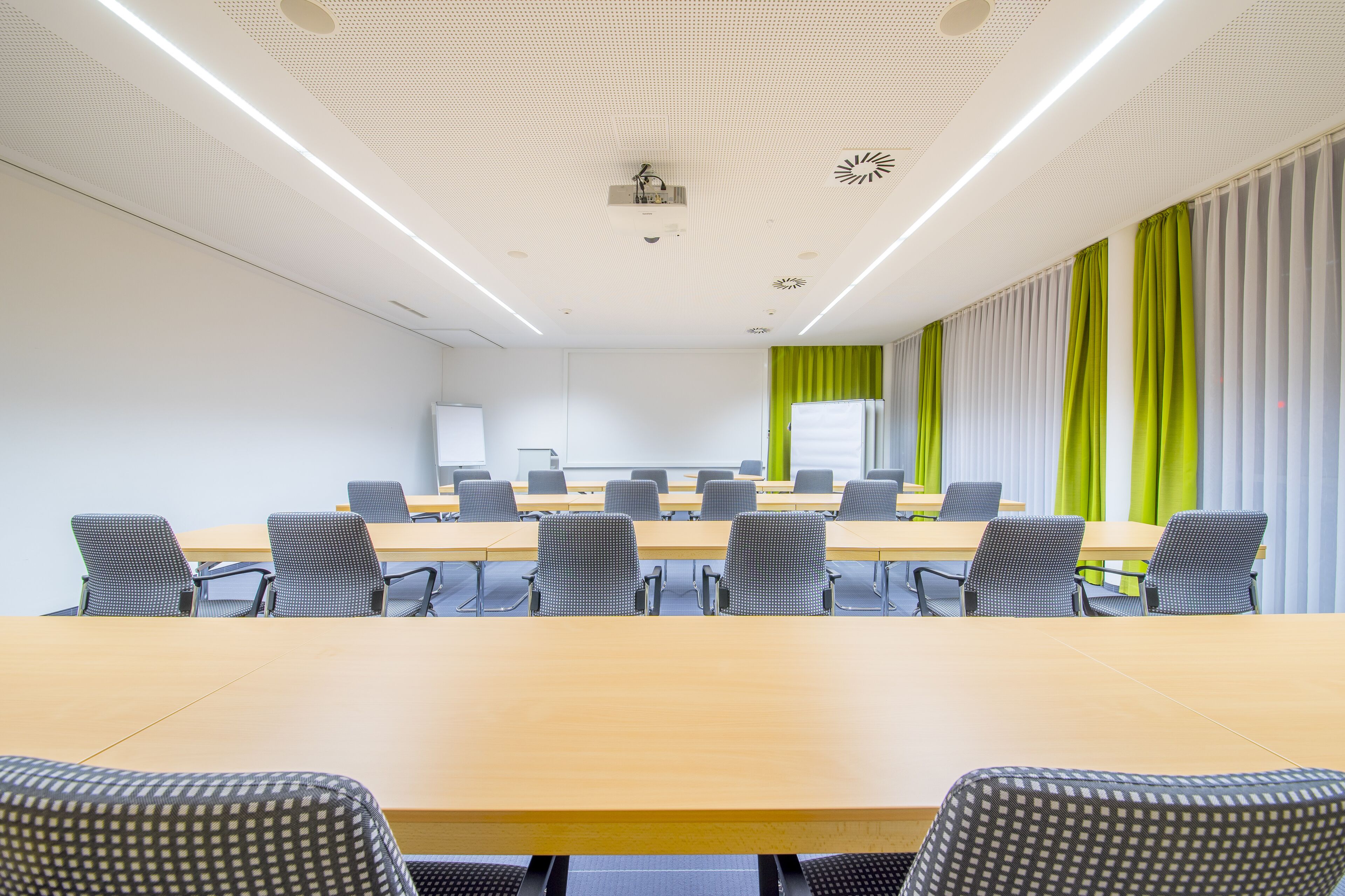 A conference room with a long table, chairs, a projector, and a whiteboard.