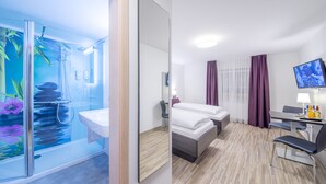 Une chambre d’hôtel avec une douche en verre, un lit, un bureau et une télévision.