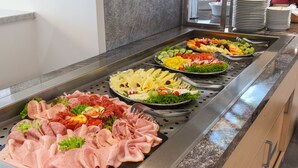 Un buffet proposant une variété de plats, notamment des viandes, des fromages et des fruits.
