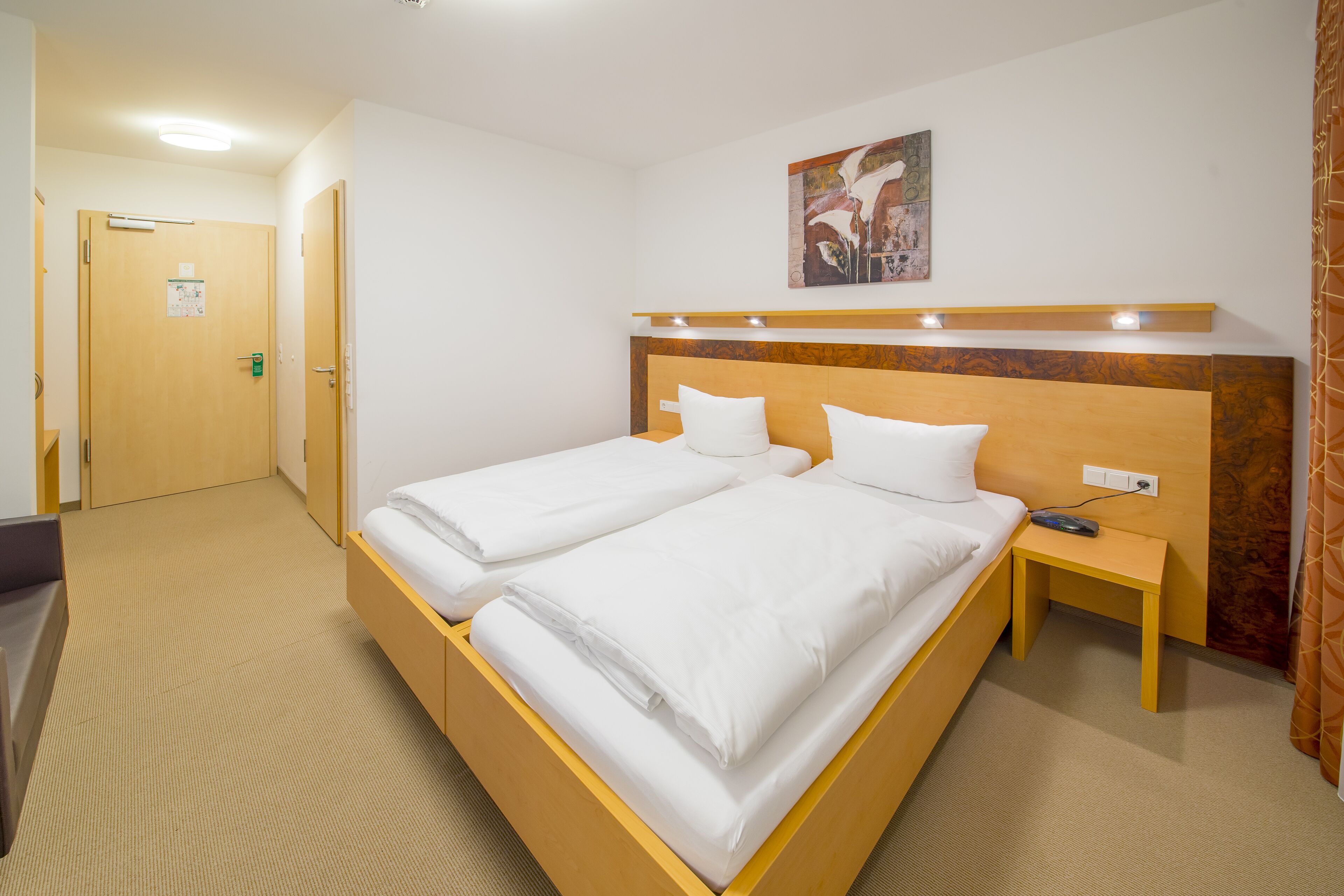 A hotel room with two beds, a desk, and a nightstand.
