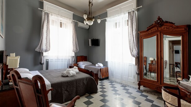 Ein Hotelzimmer mit zwei Betten, einem großen Spiegel, einer Holzkommode und einem karierten Boden.