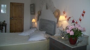 A bedroom with a bed, bedside lamps, a dresser, a wooden door, and a wall-mounted light fixture. - Chambre d'hôtes La Margotte (Forcalquier)