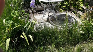 A garden setting with a round table surrounded by a metal fence, a bench, and a variety of flowers. - Chambre d'hôtes La Margotte (Forcalquier)