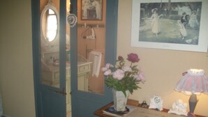 A room with a wooden desk, a vase with flowers, a lamp, and a framed picture on the wall. - Chambre d'hôtes La Margotte (Forcalquier)