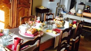 A dining area with a wooden table set for a meal, surrounded by wooden chairs. - Chambre d'hôtes La Margotte (Forcalquier)