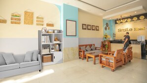 Zona de recepción con un sofá, sillas, una estantería y un mostrador con un letrero que dice "Smile Hotel".