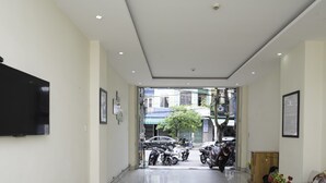 Un vestíbulo moderno y luminoso con un televisor de pantalla plana, cuadros enmarcados y una recepción.