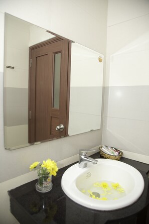 A bathroom with a white sink, a mirror, and a wooden door. - Smile Hotel (Da Nang)