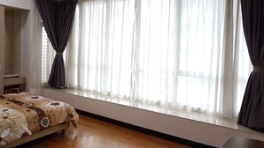 A bedroom with a bed, a wardrobe, a window with curtains, and a radiator. - Citylise Studio (Kuala Lumpur)