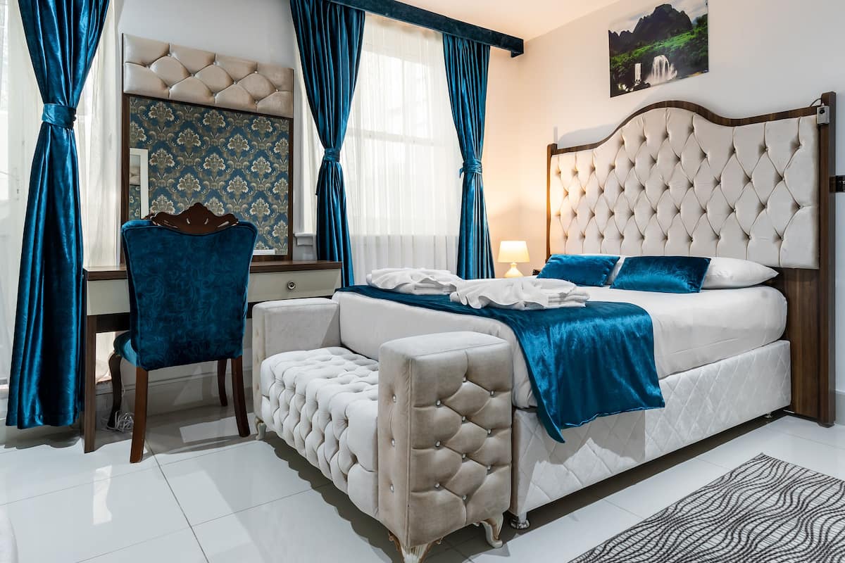 A bedroom with a large bed, a bedside table, a chair, and a mirror.