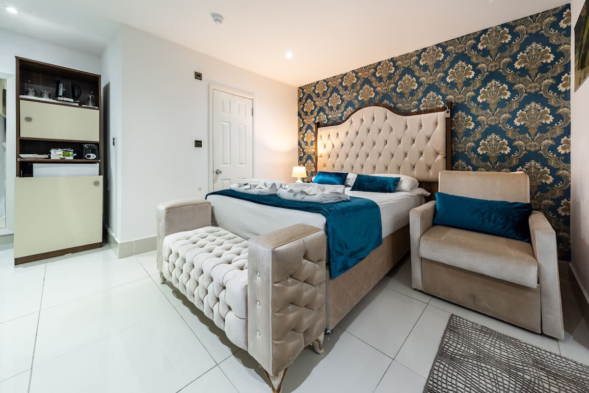 A bedroom with a bed, a chair, and a wardrobe.