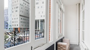 A narrow corridor with large windows, a black wall, and a grey carpet. - Vilenza Hotel (London)