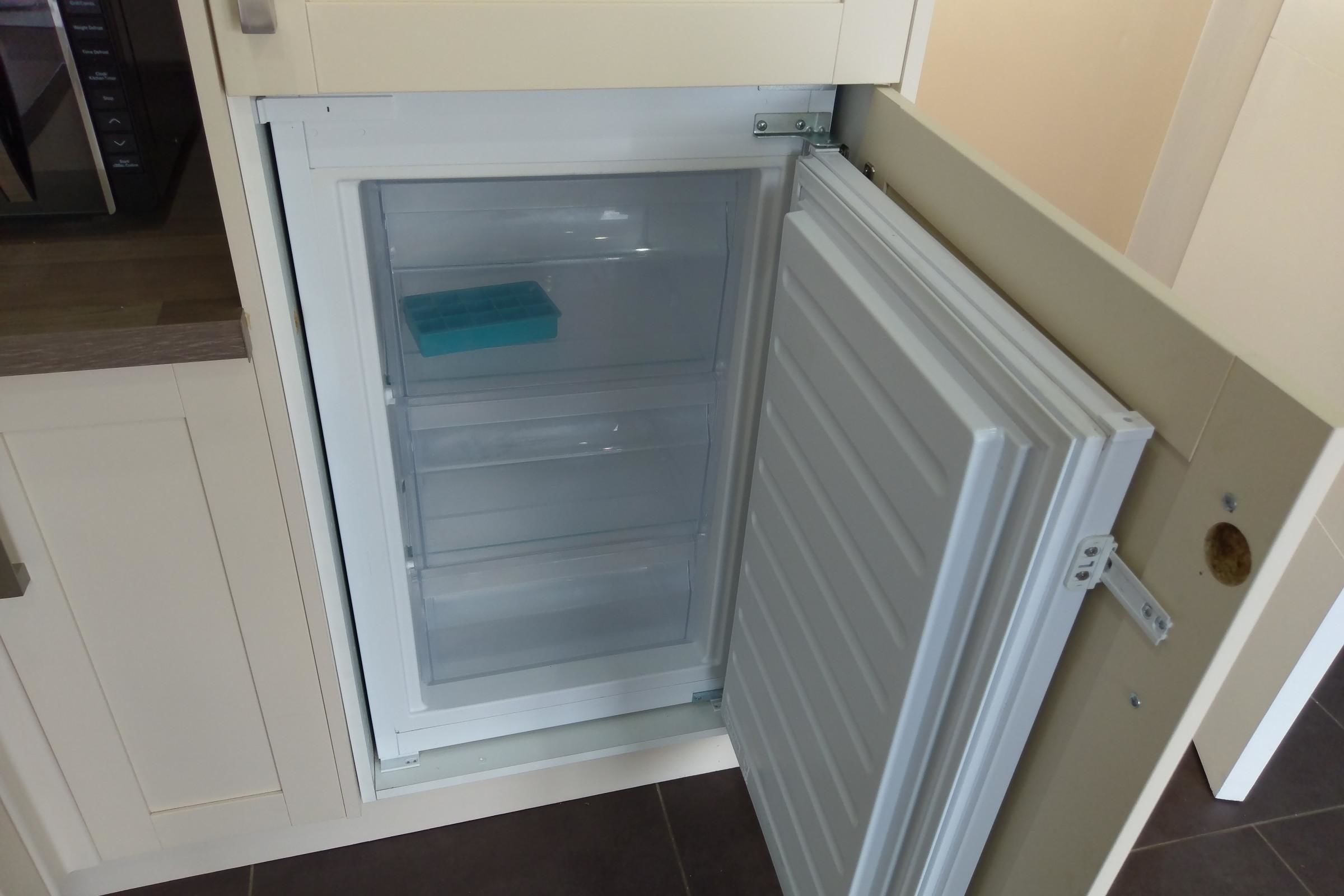 A white refrigerator with a transparent door, a blue tray, and a white handle.