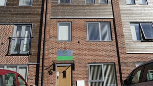 A multi-story building with a brick facade, multiple windows, and a door with a sign above it. - Jaylets Budget Glenfield (Leicester)