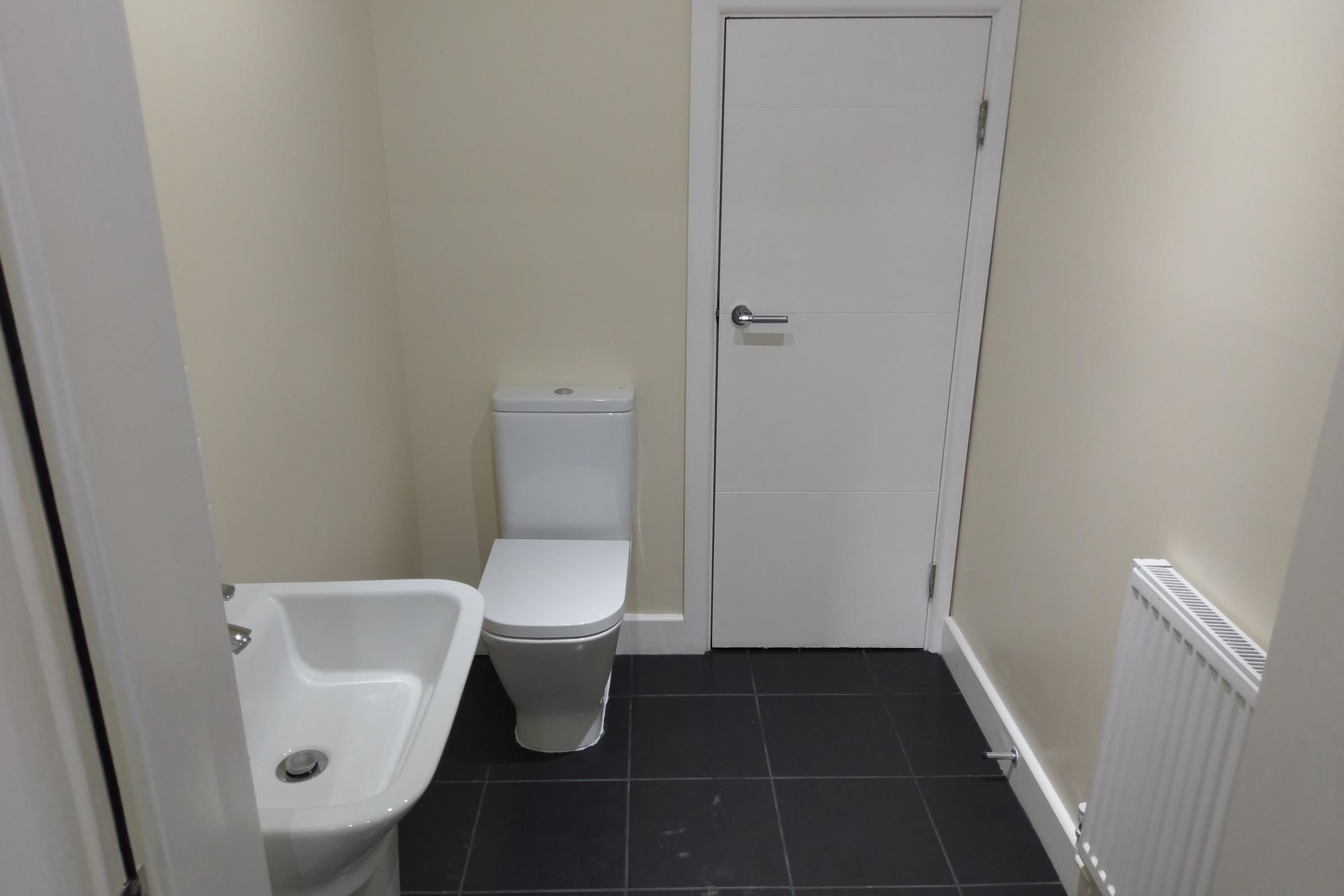 A small bathroom with a toilet, a sink, and a door.