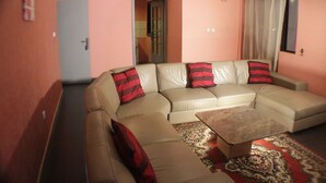Una sala de estar con un sofá seccional color beige, una mesa de centro y un tapete estampado.