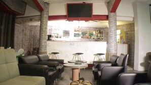 Una zona de bar con mostrador, taburetes y un televisor colgado en la pared.