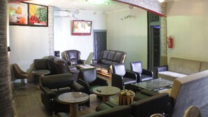 Un área de descanso con sofás y sillones de cuero, y mesitas pequeñas, con un televisor y un extintor en la pared.