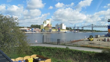 A waterfront industrial area with a bridge, a forklift, and shipping containers.