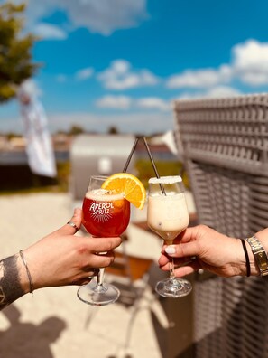 Two people holding drinks with a clear sky in the background. - Kanal-Haus "Das Gästehaus direkt am Nord-Ostsee-Kanal" (Osterrönfeld)
