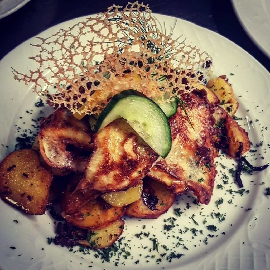 Une assiette de nourriture comprenant du poulet grillé, des pommes de terre et un décor en forme de filet.
