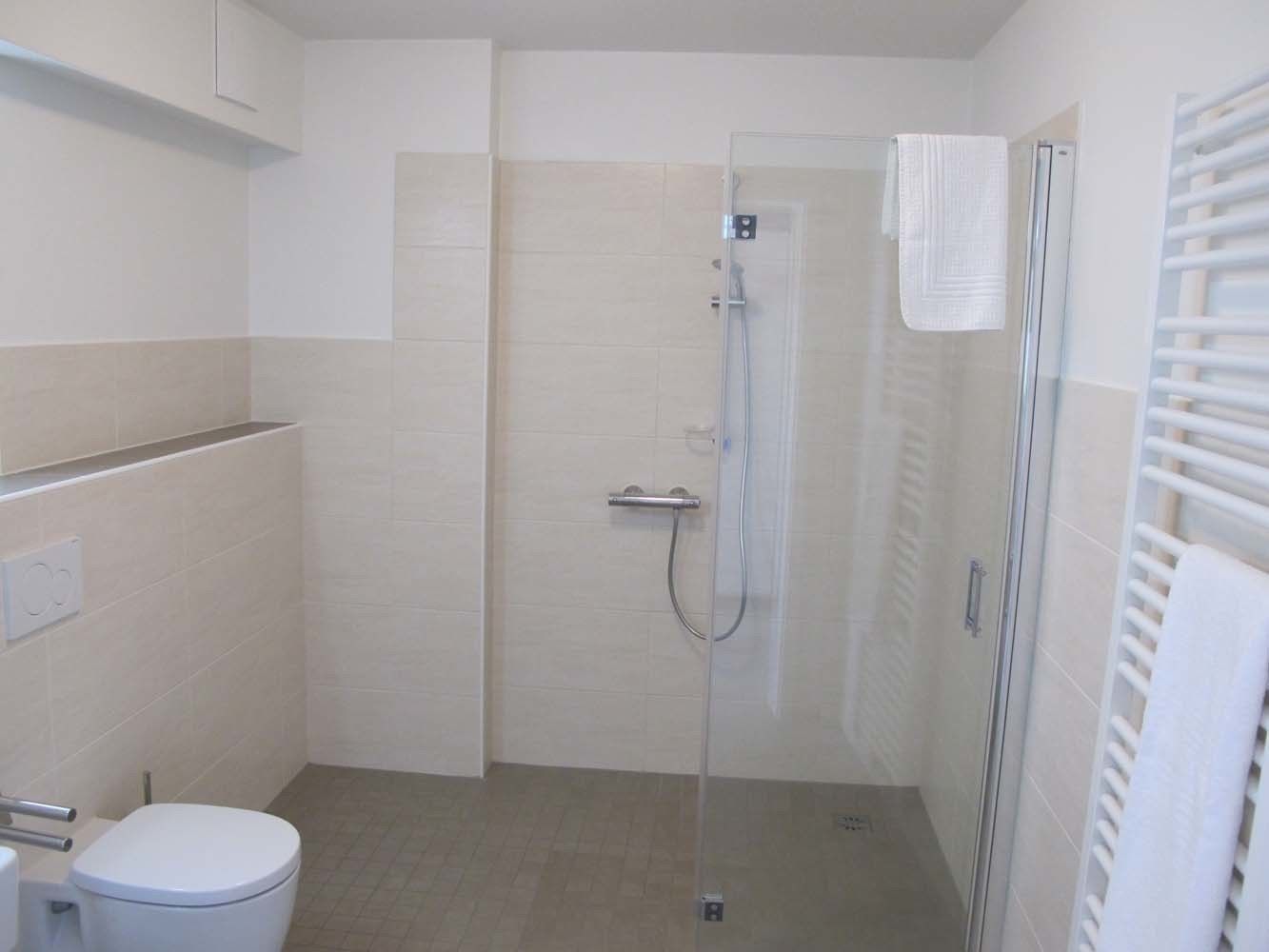 A bathroom with a toilet, a shower with a glass door, and a towel rack.